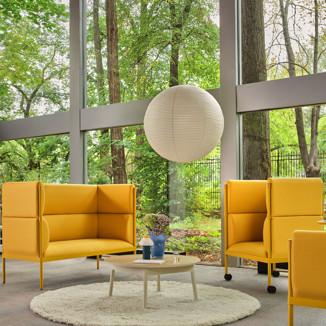 Bright yellow modular sofas with a soft, modern design, set against a backdrop of greenery and natural light.