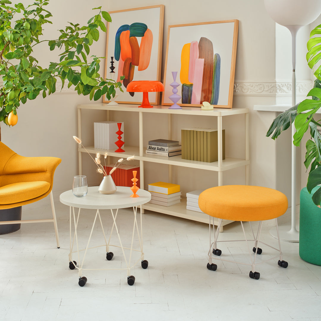 "Bright orange chair and ottoman with white tabletop and colorful artwork in a modern living space."