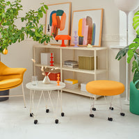 "Bright orange chair and ottoman with white tabletop and colorful artwork in a modern living space."