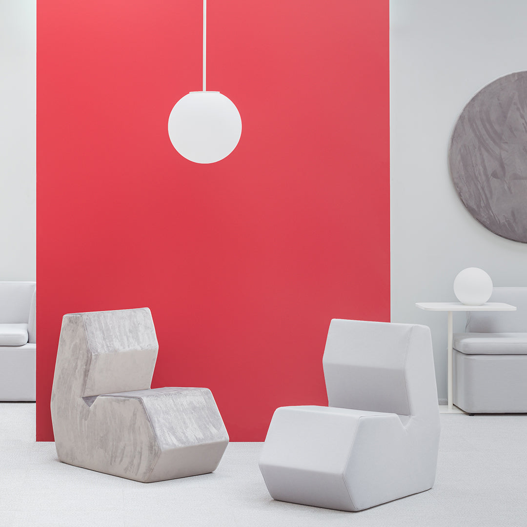 "Modern gray and white chairs against a bold red wall, featuring minimalist geometric shapes and clean lines."