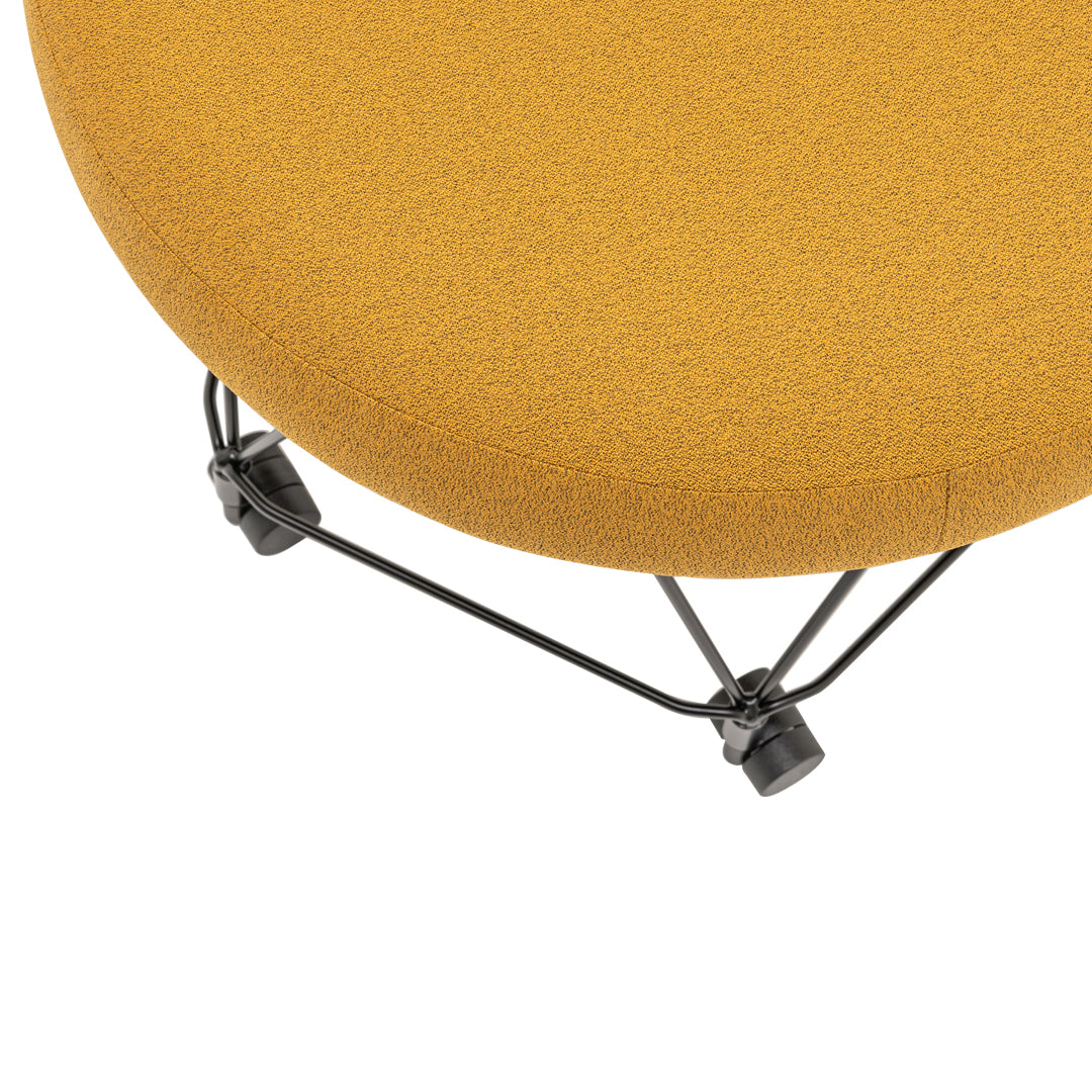 Round mustard yellow cushion with a textured surface, supported by a sleek black wire frame.