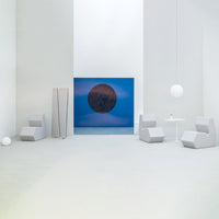 Modern room showcasing soft gray furniture, a vibrant blue wall art with a dark circular pattern, and minimalist decor.