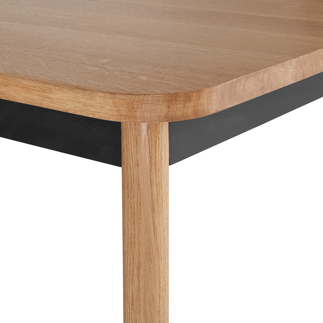 Wooden table with a natural oak finish and sleek black edges, showcasing a minimalist design and smooth textures.