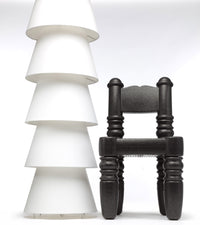 "Stylish black chair beside elegant stacked white bowls, showcasing a modern color contrast and unique patterns."