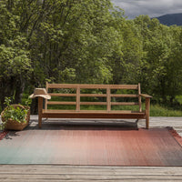 Colorful gradient rug featuring warm terracotta and soft teal hues, perfect for outdoor settings.