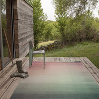 Gradient outdoor rug featuring soft greens, pinks, and blues in a subtle textured pattern. Ideal for patios.