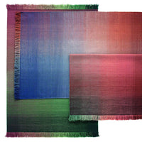 Multicolored rugs in gradient hues of blue, green, and red with fringed edges and smooth textures.