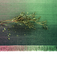 Gradient green textile with subtle texture, featuring a fringe edge, and scattered leaves for a natural touch.