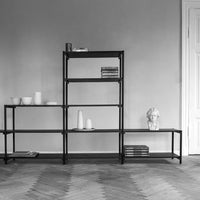 "Black metal shelving unit with minimalist design and geometric patterns, set against a neutral wall."
