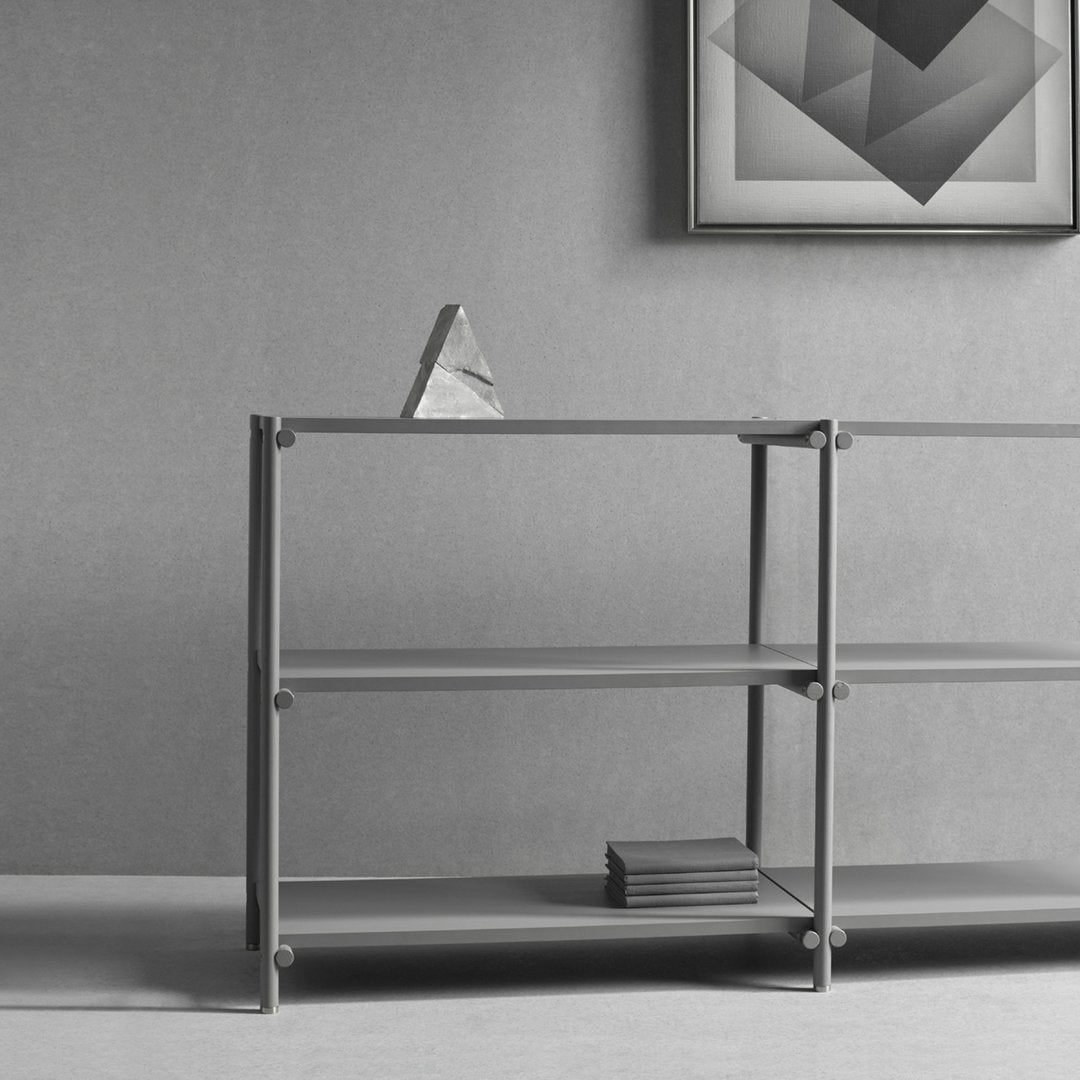 Modern gray shelving unit with clean lines and a minimalist design, featuring a smooth finish and geometric patterns.
