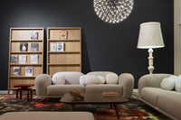 Modern lounge with neutral beige sofas, bright white cushions, and a patterned multicolor area rug against a dark wall.