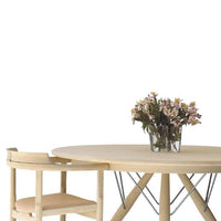 Round wooden table with a natural finish, paired with a light-colored chair and a bouquet of flowers. Minimalist design.