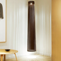Tall, cylindrical pendant light in dark brown with delicate vertical strands, casting soft light patterns on the floor.