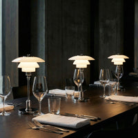 Elegant white lamps with curved shades on a sleek dark wooden table, complemented by clear glassware.