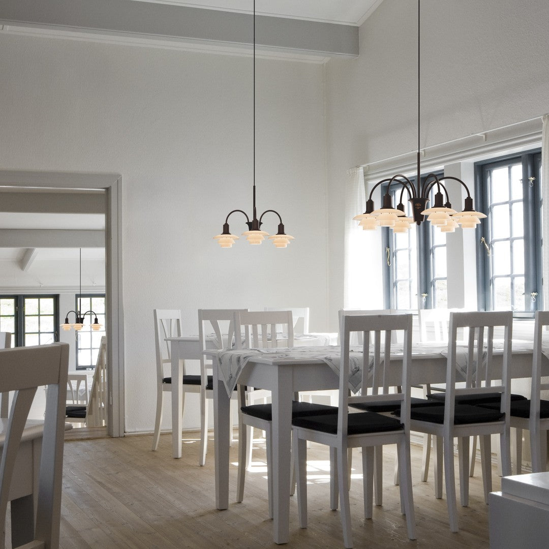Modern dining room with white furniture, black cushions, and warm light fixtures against a neutral backdrop.