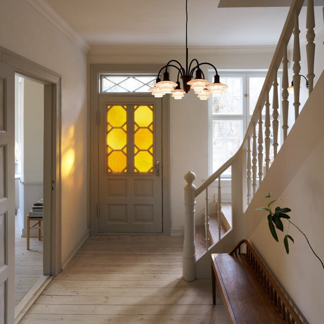 Modern hallway with gray walls, light wood flooring, and a yellow patterned door accented by a stylish chandelier.