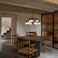 Modern dining room featuring a round black table, wooden chairs, and warm beige walls with gray tiled flooring.