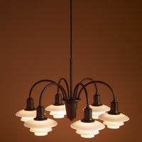 Elegant black pendant lamp with white glass shades, featuring a smooth, modern design against a warm brown background.