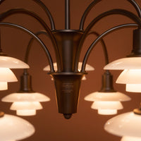 "Bronze chandelier with white glass shades creating a sleek and modern design."