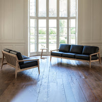 Black leather sofa with light wood accents, featuring clean lines and a modern design in a spacious, bright room.