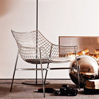Stylish wire chair in silver with a modern geometric pattern, set against a warm, neutral-toned backdrop.
