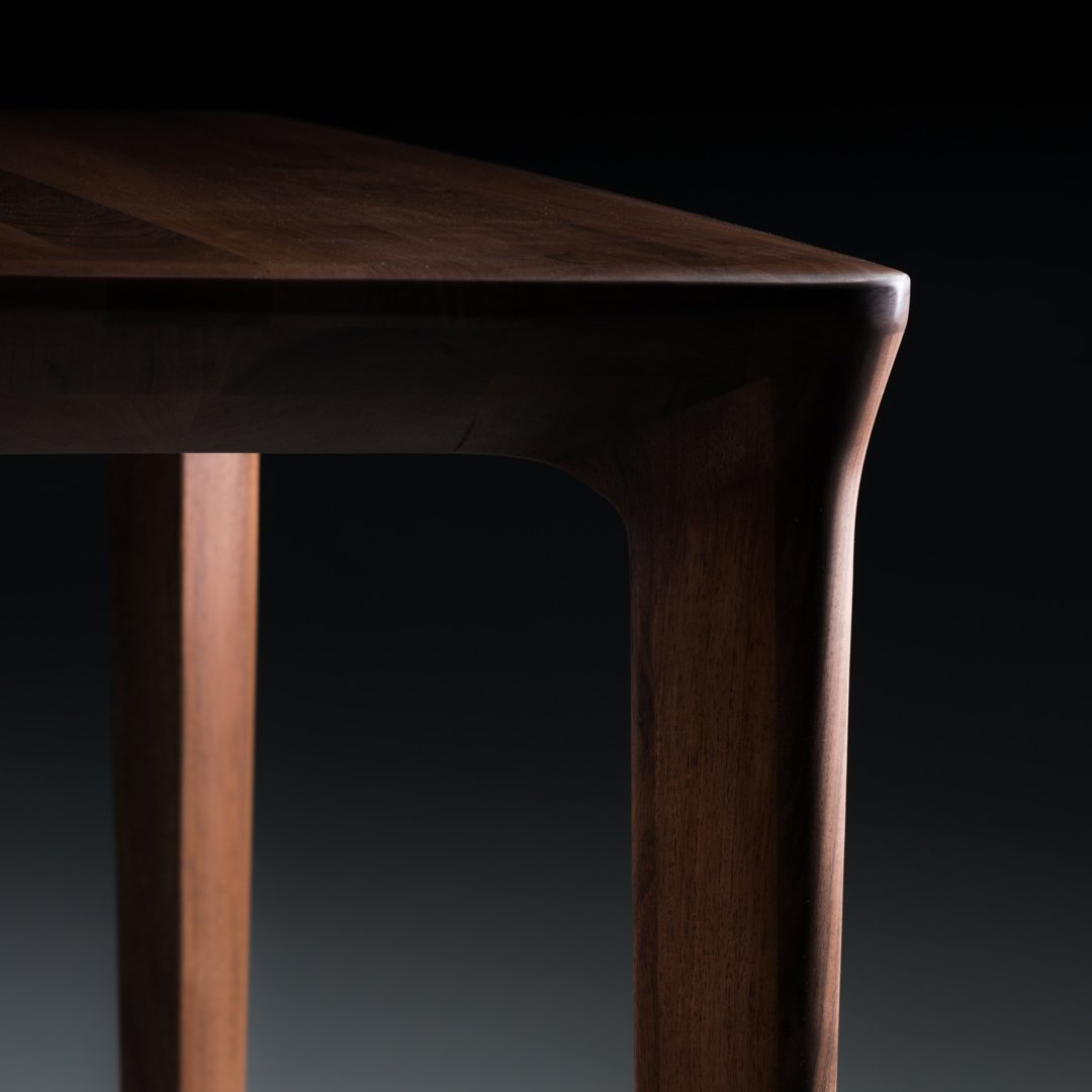 Elegant walnut wood table with smooth, rich brown tones and subtle grain patterns, highlighting craftsmanship and design.