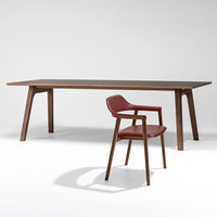 Modern wooden dining table with rich brown finish and a sleek red upholstered chair, featuring a minimalist design.