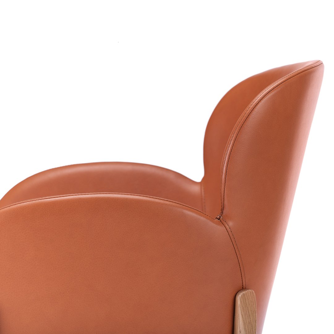 "Close-up of a sleek, orange-brown leather chair with smooth curves and a minimalist design."