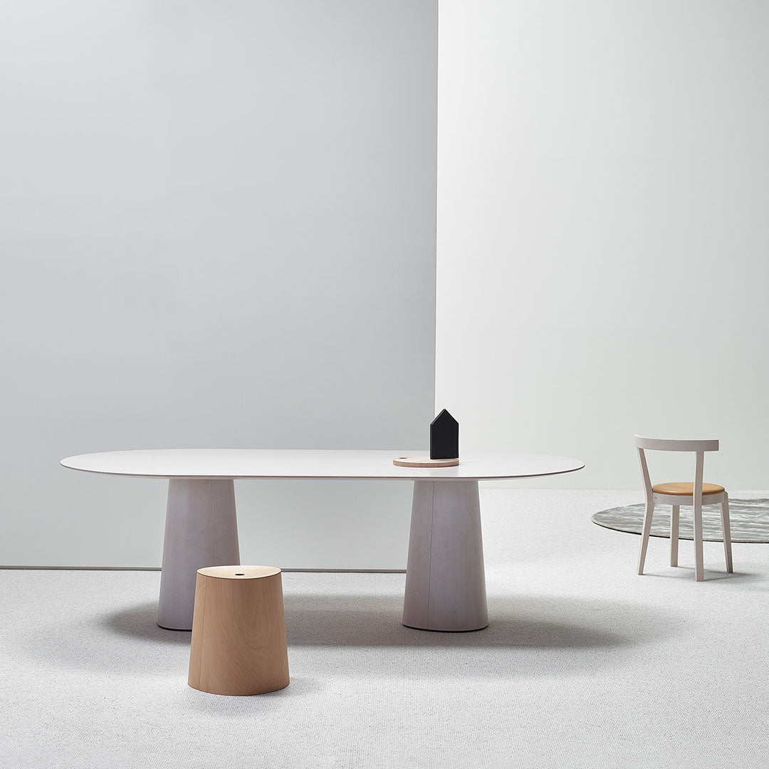 Modern minimalist table set with white, light wood, and gray tones, featuring smooth surfaces and simple shapes.