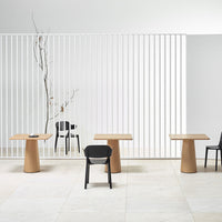 Light wood tables with smooth, natural finishes, paired with sleek black and white chairs in a minimalist setting.