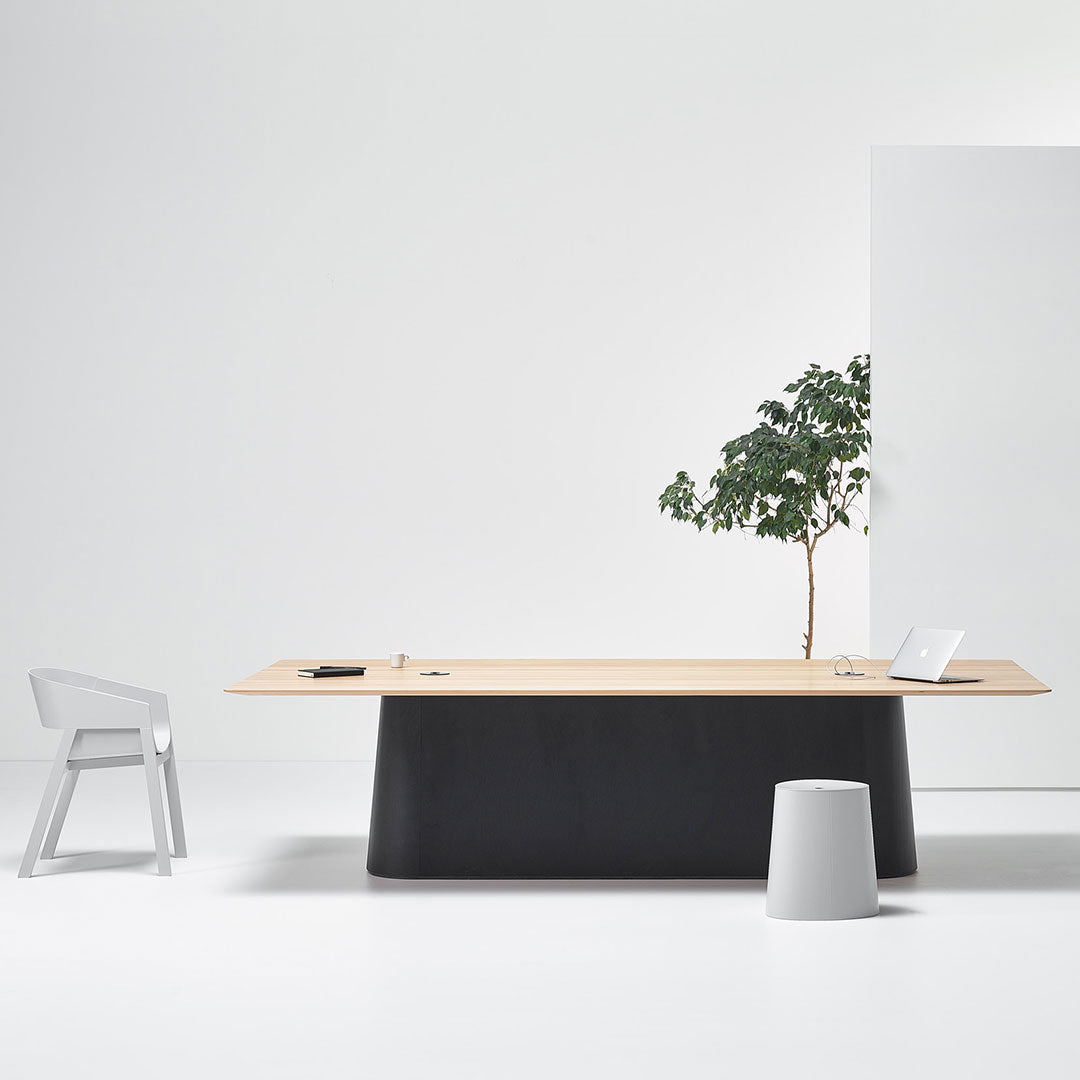 Modern desk with a light wood top and matte black base, paired with a sleek gray chair and white decor elements.