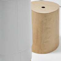 White cylindrical object next to a smooth, natural wood round stool, showcasing simple, modern design and neutral tones.