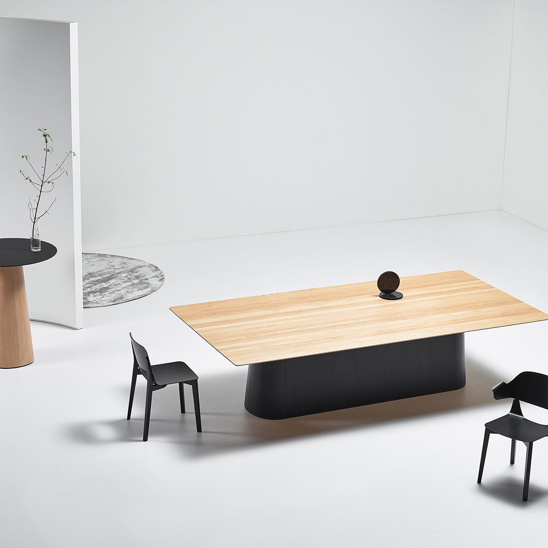 Modern dining table with a light wood top, sleek black base, and minimalistic black chairs on a neutral backdrop.