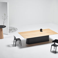 Modern dining table with a light wood top, sleek black base, and minimalistic black chairs on a neutral backdrop.