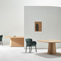 Modern interior featuring natural wood tones, deep green chairs, and a neutral color palette for a stylish look.