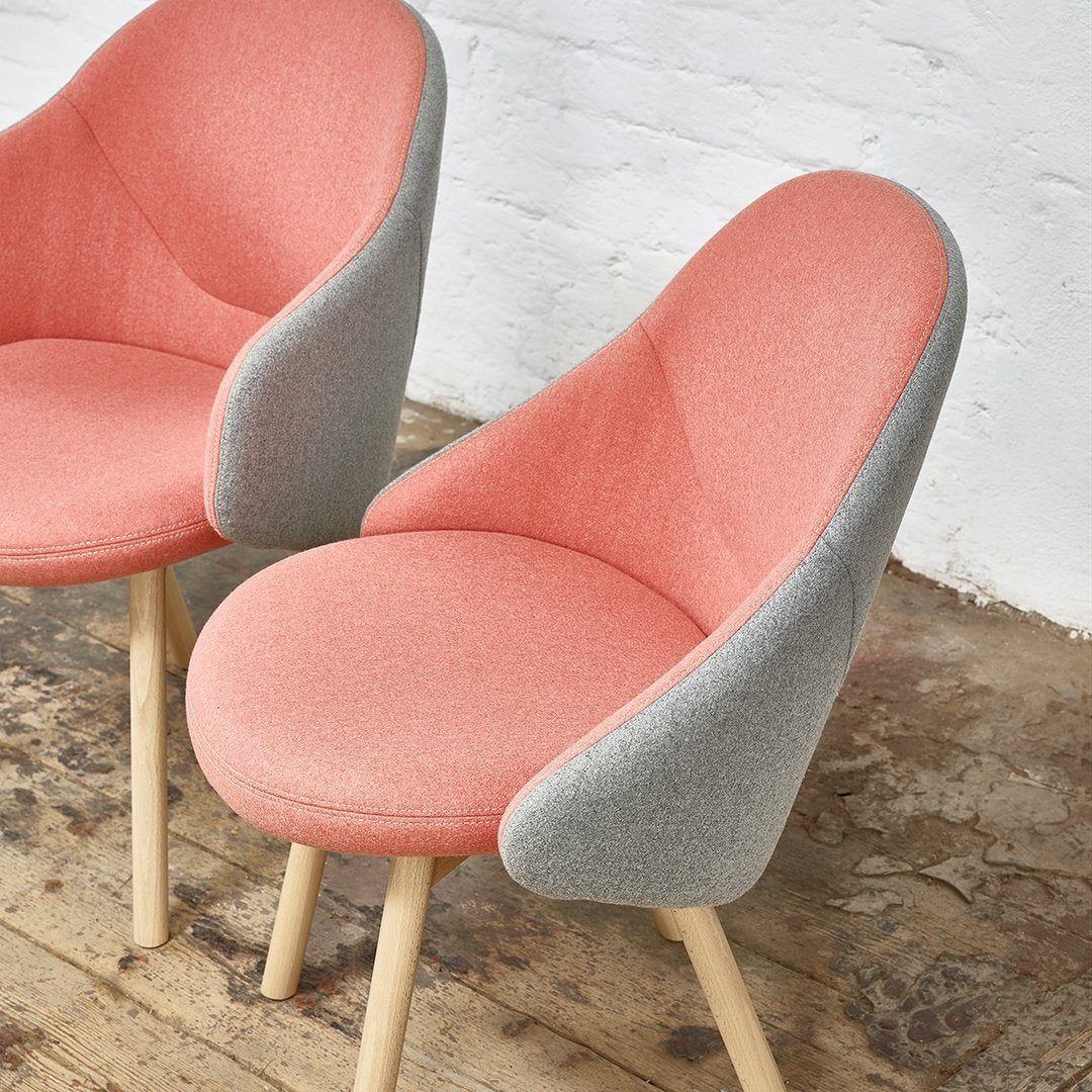 Pink and gray modern chairs with smooth curves and textured fabric against a wooden floor backdrop.