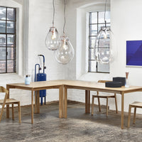 Modern wood dining table in natural finish, accented with clear glass pendant lights and blue decor.