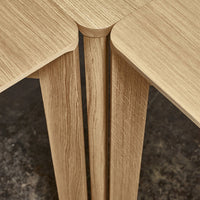 Close-up of light wood table with natural grain patterns and smooth edges, highlighting its minimalist design.