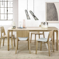 Light wood dining table with pale blue chairs, minimalist design, modern decor, and industrial pendant lights.