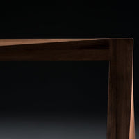"Close-up of sleek dark wood table edge with a smooth finish against a black background."