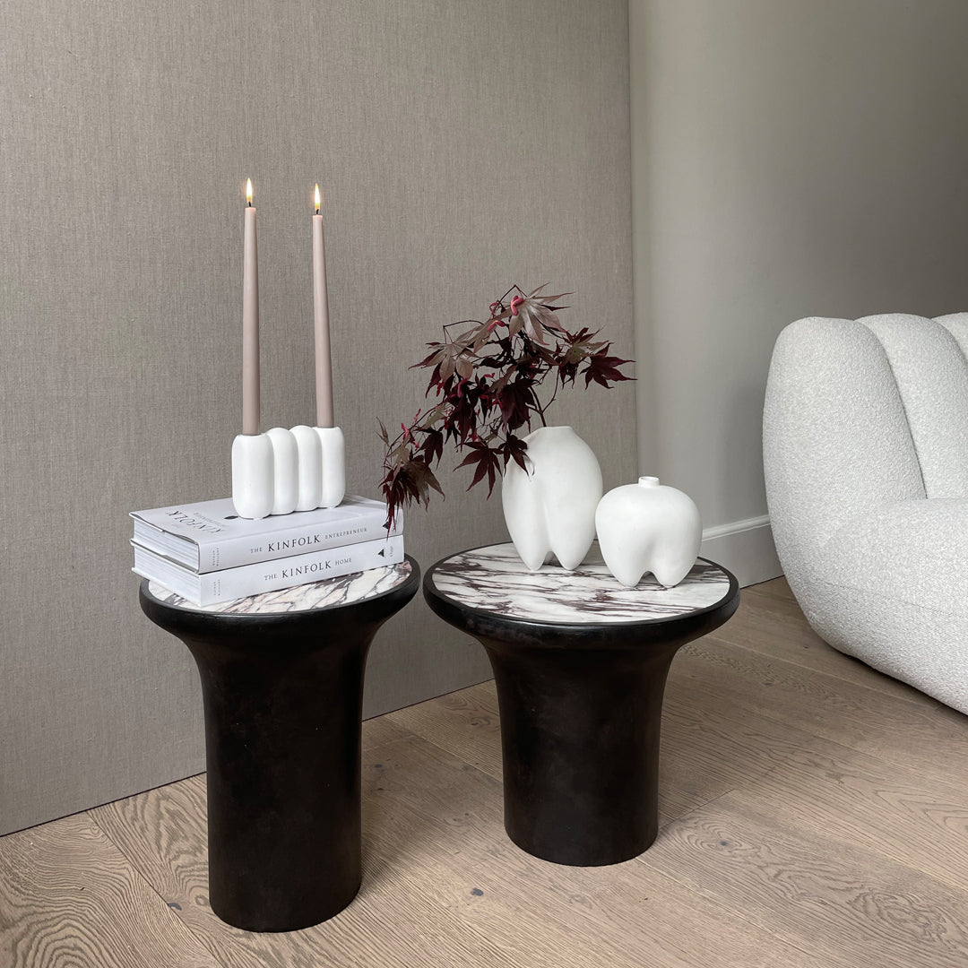 Black and white marble side tables with smooth surfaces and modern curves, styled with minimalist decor accents.