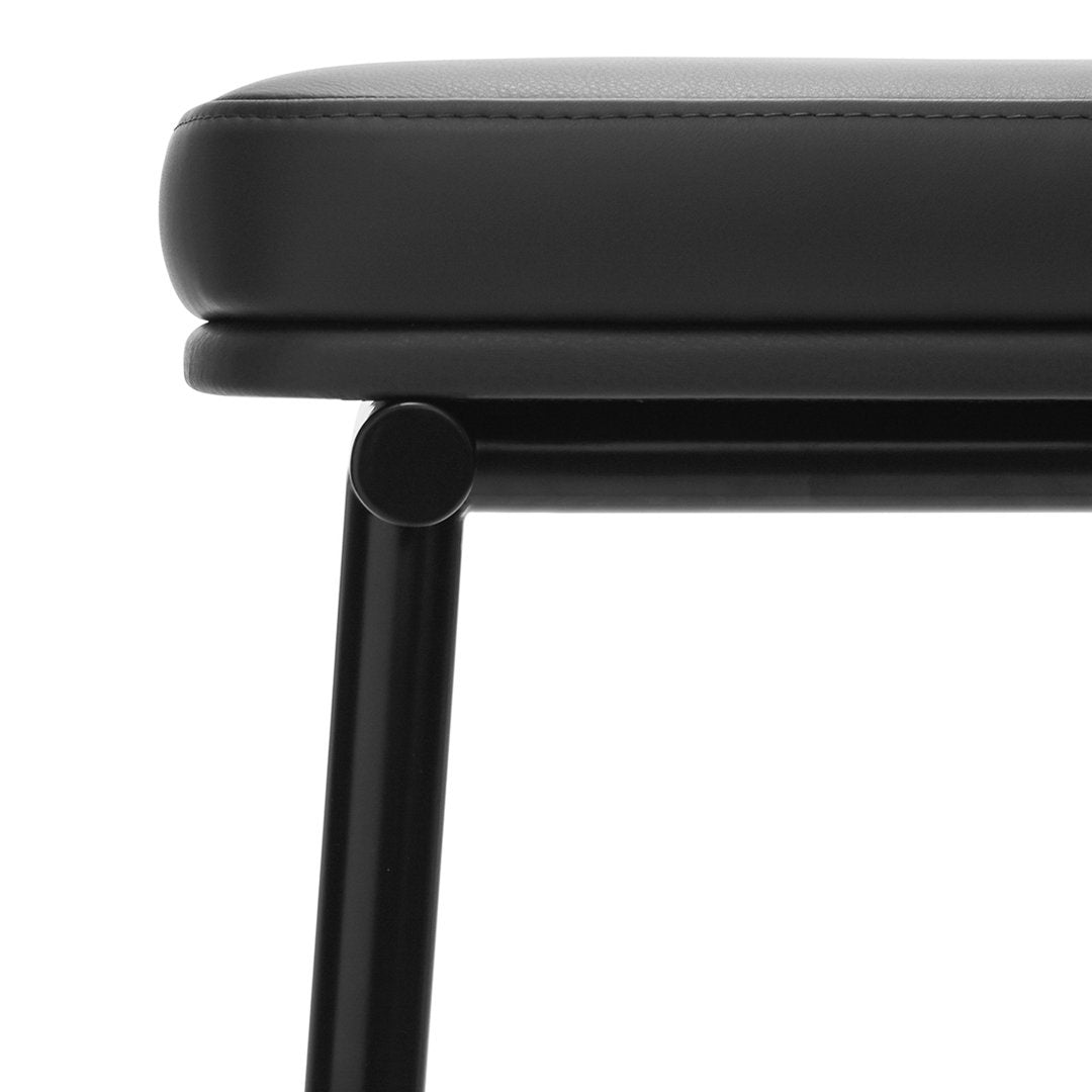 Black padded seat with sleek black metal legs, featuring a minimalist design and smooth surface.