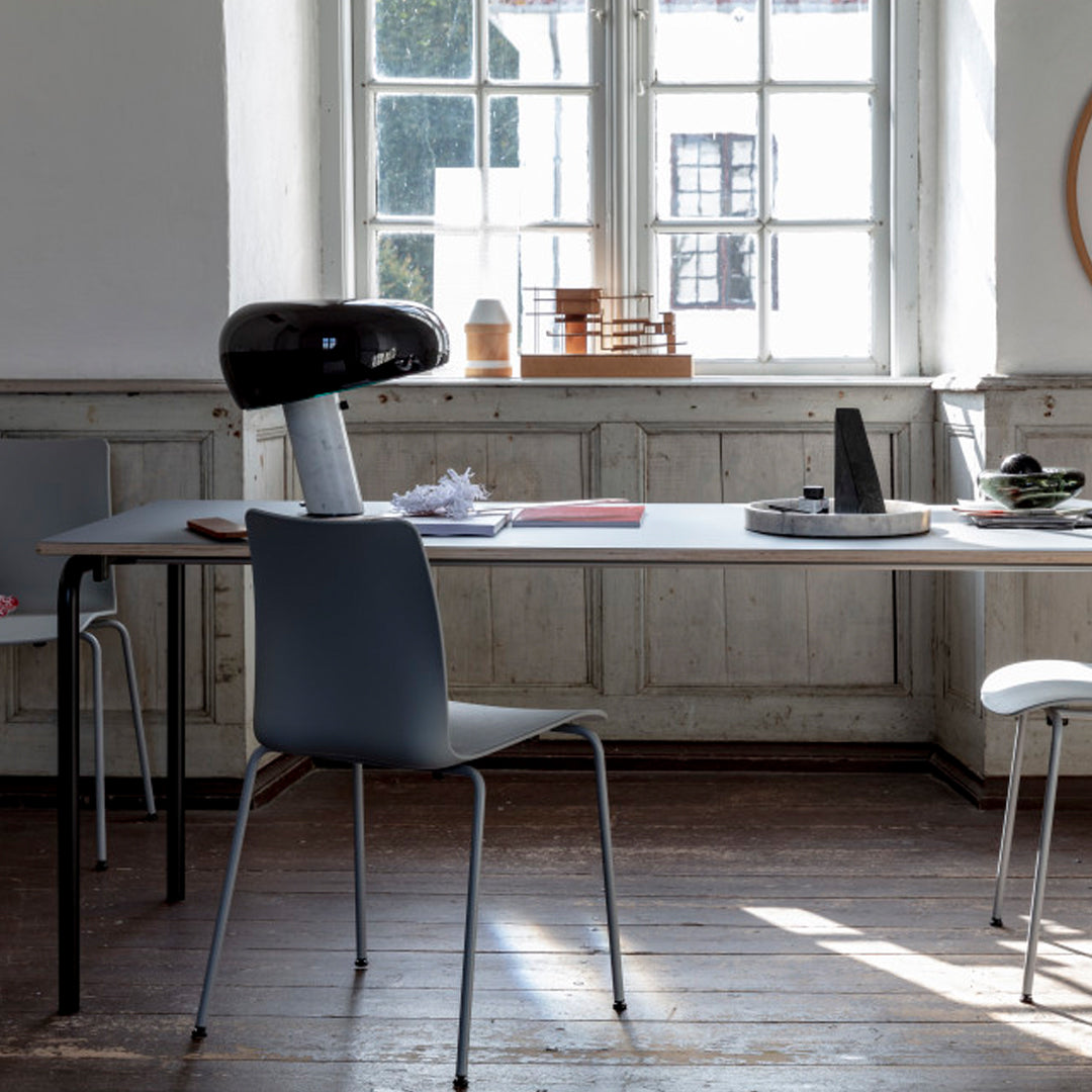 Modern minimalist dining room with a grey chair, black lamp, and wooden accents in a light, airy space.