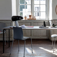 Modern minimalist dining room with a grey chair, black lamp, and wooden accents in a light, airy space.