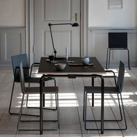 Modern black table with gray chairs and minimalistic decor, featuring clean lines and soft shadows on a wooden floor.