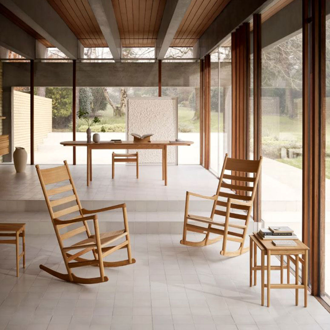 Natural wood rocking chairs, light beige flooring, and warm wooden beams create a serene, modern aesthetic.