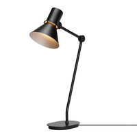 Black desk lamp with a matte finish and a gold interior shade, featuring a sleek, minimalist design.