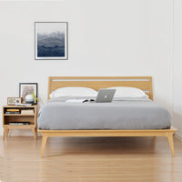 Modern wooden bed frame with a light oak finish, complemented by a soft gray duvet and simple, neutral decor.
