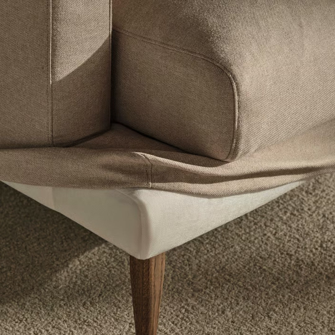 Tan and beige fabric corner of a sofa with wood legs, showcasing clean lines and a smooth finish.