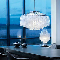 "Elegant chrome chandelier with textured white glass, casting soft light against a serene blue backdrop."